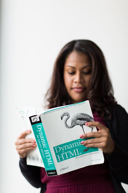 A gardener, dressed in a grey uniform with reflective yellow stripes and a brown hat, is walking through a curved, glass-enclosed greenhouse. He is carrying freshly cut green foliage in his right hand